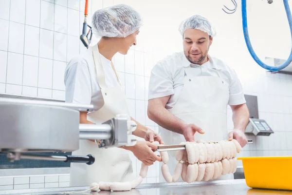 Equipe de açougueiros enchendo salsichas na indústria da carne — Fotografia de Stock