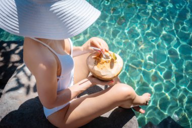 Beyaz mayo giymiş bir kadın havuzda dinleniyor.