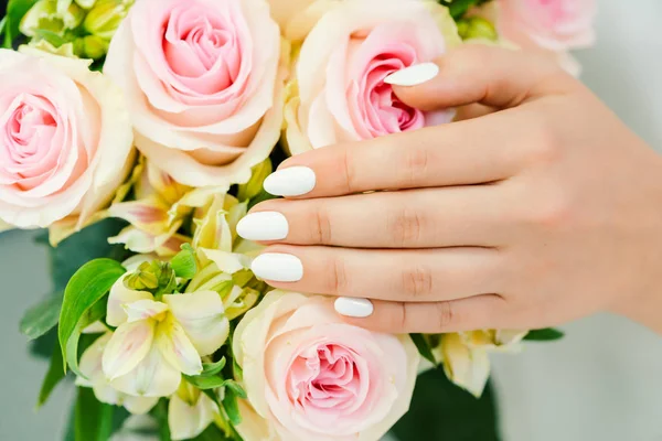 Pregos de mulher jovem com manicura branca em uma flor de rosa — Fotografia de Stock