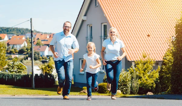 Familia feliz corriendo frente a su nuevo hogar — Foto de Stock