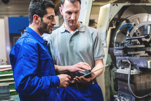 Zwei Arbeiter diskutieren vor der CNC-Drehmaschine ein Projekt — Stockfoto