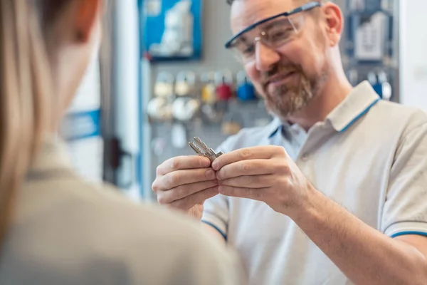 Slotenmaker toont vrouw sleutel blanks — Stockfoto