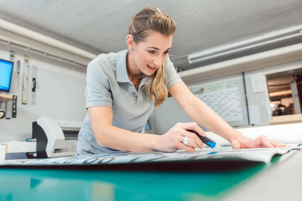 Frau schneidet Schilder oder Vinylfolien zur Herstellung von Werbematerial — Stockfoto