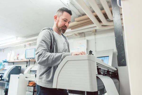 Hombre preparando impresora de gran formato para un trabajo de impresión — Foto de Stock