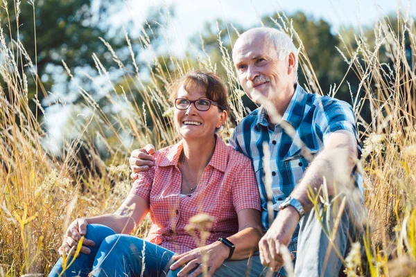 楽しんで草に座っている年配のカップル — ストック写真