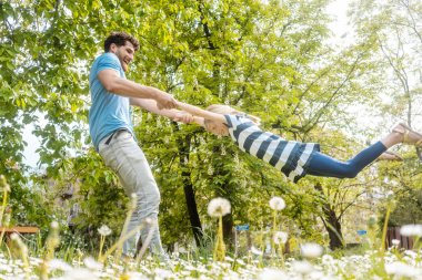 Babam kızıyla çimenlerde oynuyor.