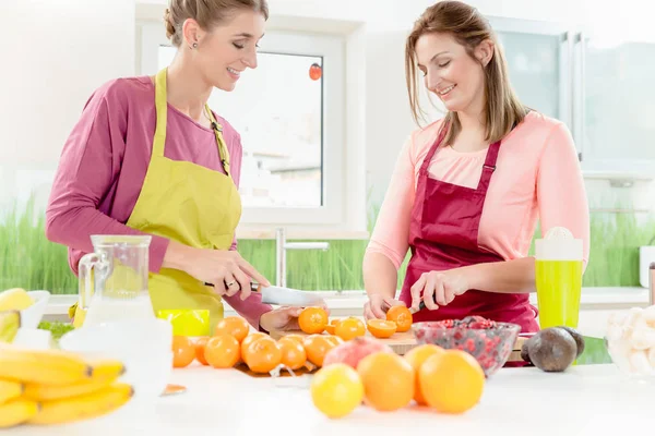 Zwei Frauen schneiden saftige Orangen — Stockfoto