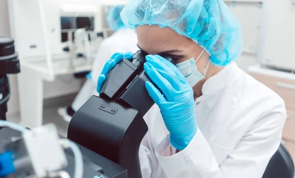 Kvinna-forskare som arbetar på mikroskopet — Stockfoto