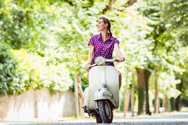 Mujer joven montando scooter viejo — Foto de Stock