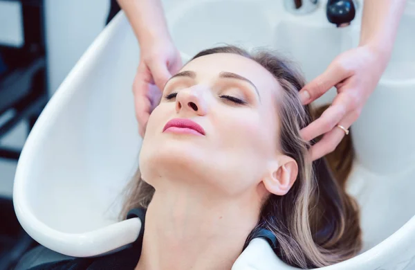 Hairdresser washing hair of client in her shop — Stock Photo, Image