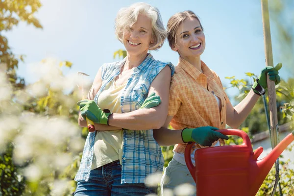 Jong en senior vrouw poseren voor foto in hun tuin — Stockfoto