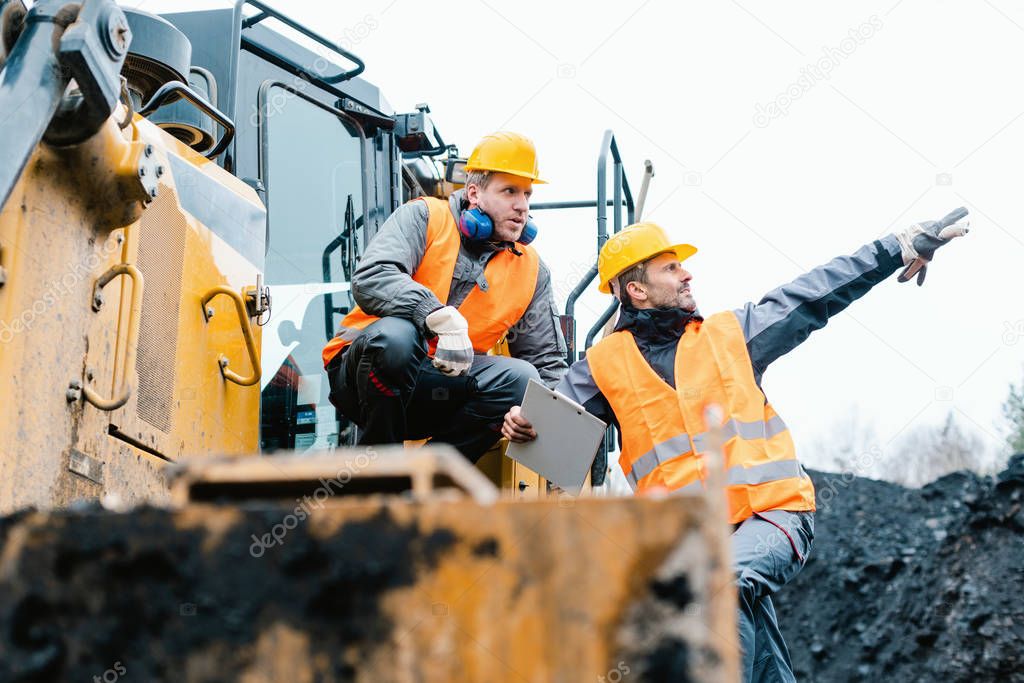 Foreman showing worker in open-cast mining pit direction