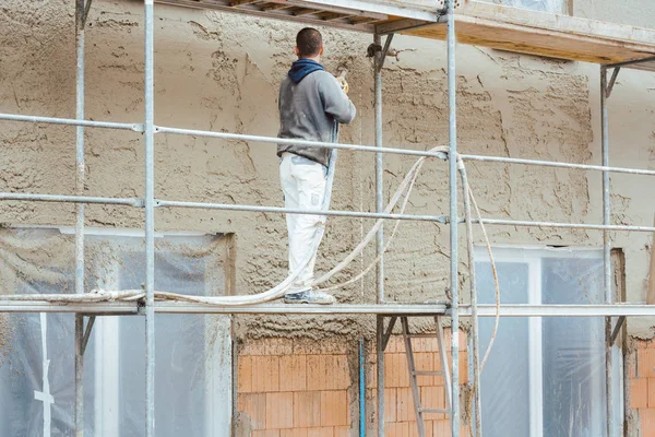 Werknemer bepleistering buitenste muur van nieuw gebouwde huis — Stockfoto