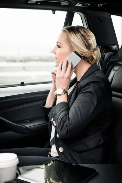 Zakenvrouw die smartphone in de auto gebruikt — Stockfoto