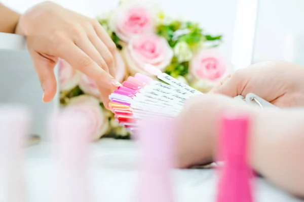 Vrouw tijdens manicure kiezen van een nagel kleur — Stockfoto