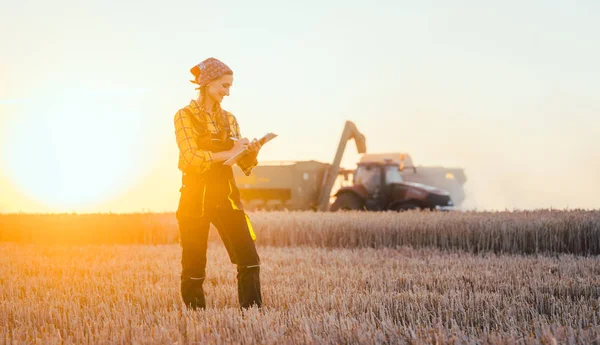 Farmer woman and combine harvester on wheat field — Stock Photo, Image