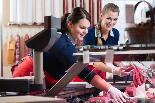 Zwei Verkäuferinnen in Metzgerei stopfen die Fleischauslage — Stockfoto