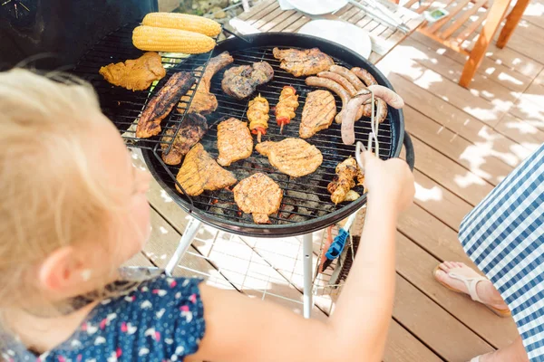 Bambina grigliare la carne per il barbecue — Foto Stock