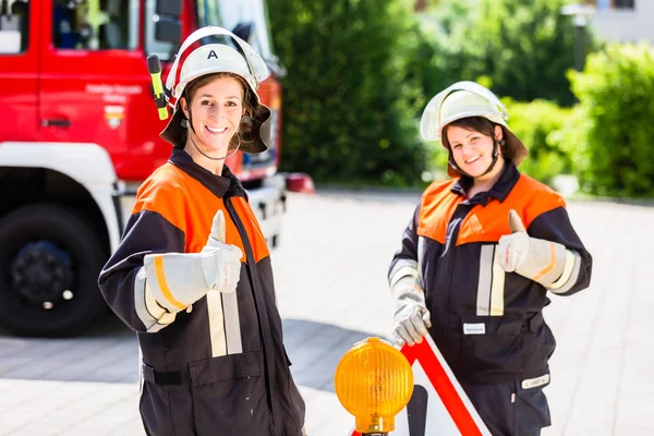 Female fire fighters setting up attention sign — Stock Photo, Image