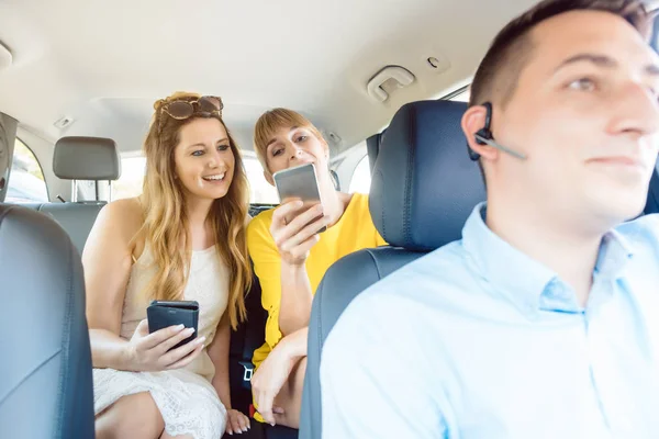 Beste Freundinnen posten in den sozialen Medien im Taxi — Stockfoto