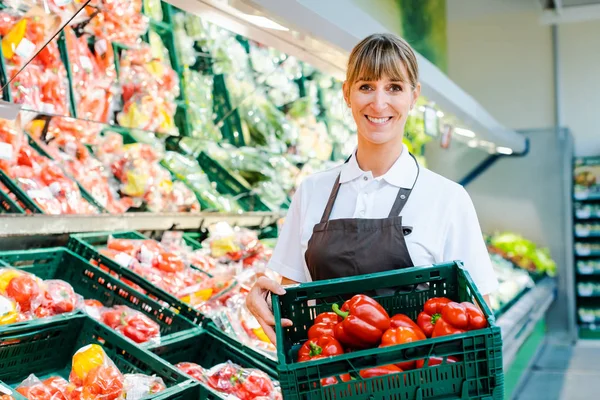 Urzędnik w supermarkecie pokazujący świeże warzywa — Zdjęcie stockowe