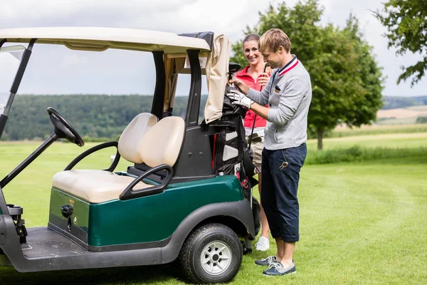 Couple debout près de la voiturette de golf — Photo