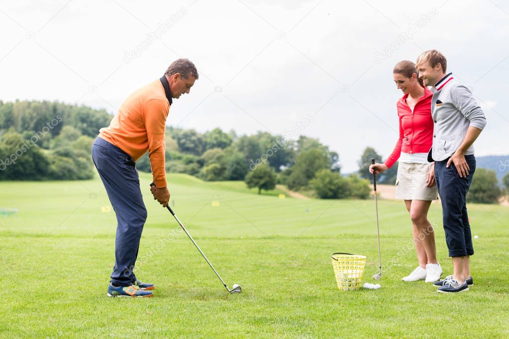 Couple looking at male coacher taking a shot