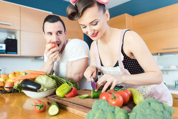 Um homem preguiçoso está a ver a mulher a preparar a comida. — Fotografia de Stock