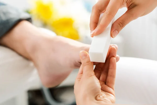 Vrouw podotherapeut polijsten voeder van mannen tijdens de pedicure — Stockfoto