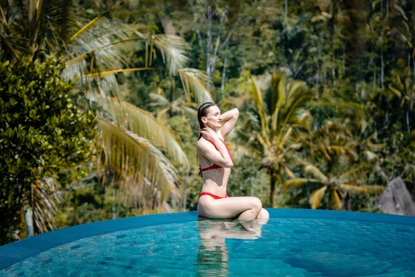 Woman in tropical vacation sitting in the water of pool — Stock Photo, Image