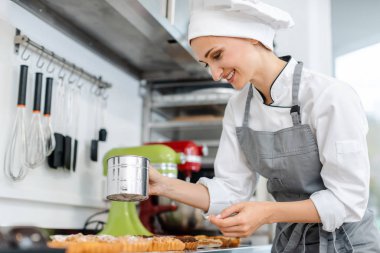 Patissier küçük kek üzerine kakao tozu koyarak