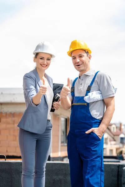 Arquitecto y trabajador de la construcción en el sitio dando pulgares hacia arriba — Foto de Stock