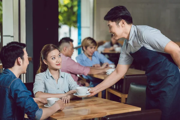 Camarero sirviendo café a una joven en el café — Foto de Stock