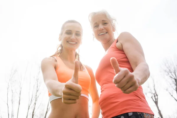 Senior vrouw en dochter geven duimen omhoog voor sport — Stockfoto