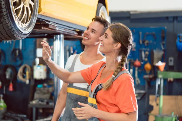 Two dedicated auto mechanics checking the modified wheels of a tuned car — Stock Photo, Image