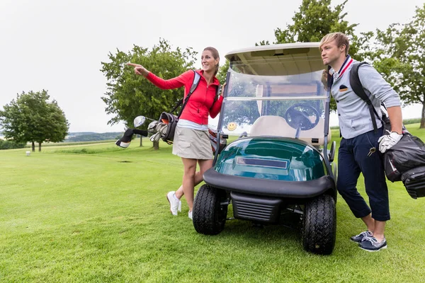 Coppia in piedi vicino golf cart — Foto Stock