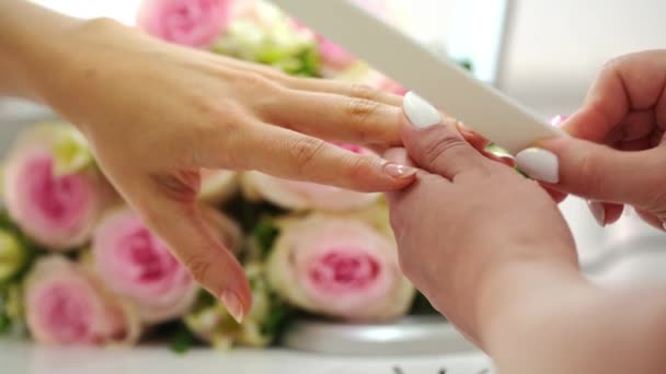 Primer plano de las manos de una manicurista limando las uñas de una joven — Vídeos de Stock