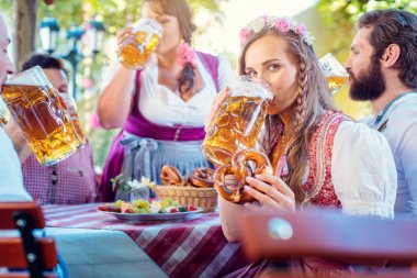 Tracht 'taki kadın bira içerken kameraya bakıyor.
