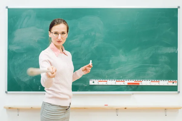 Professeur strict pointant avec pointeur devant le tableau noir — Photo