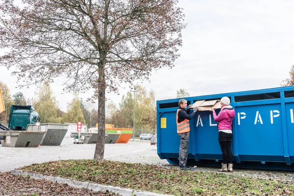 Frau und Mann legen Altpapier in Container auf Recyclinghof — Stockfoto