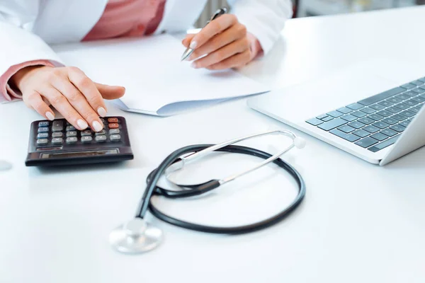 Doctor usando calculadora escribiendo facturas y haciendo contabilidad — Foto de Stock