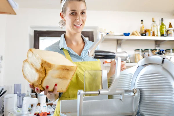 Mujer sonriente sosteniendo pan en la cocina — Foto de Stock