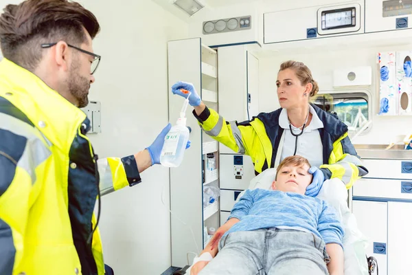 Emergency doctor and paramedic giving infusion in ambulance — Stock Photo, Image