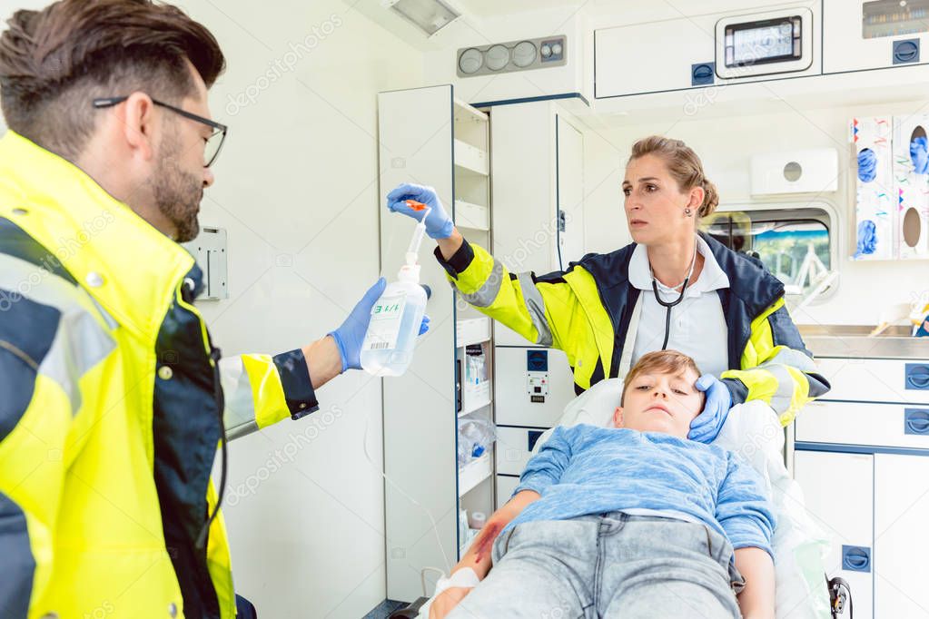 Emergency doctor and paramedic giving infusion in ambulance