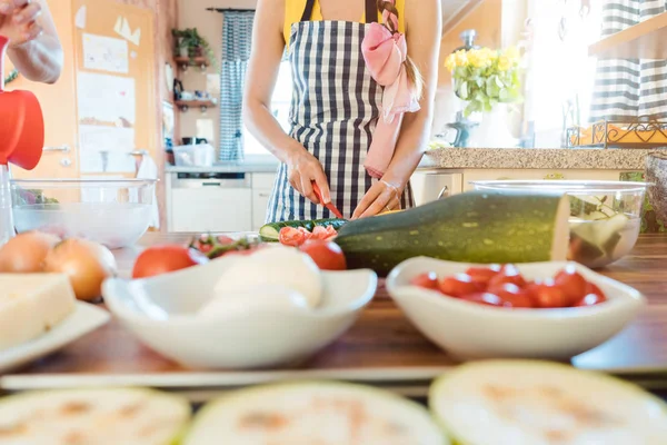 Женщина кладет овощи в миску, чтобы сделать салат — стоковое фото