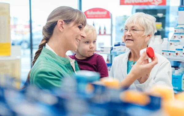 Vriendelijke apotheker, moeder en kind plezier in de apotheek — Stockfoto