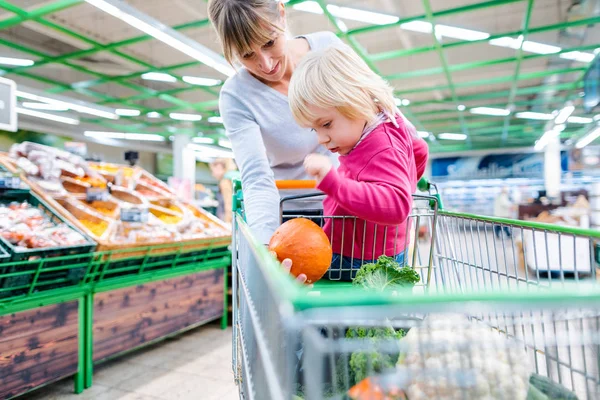 Mutter reitet mit Kleinkind im Einkaufswagen des Supermarktes — Stockfoto