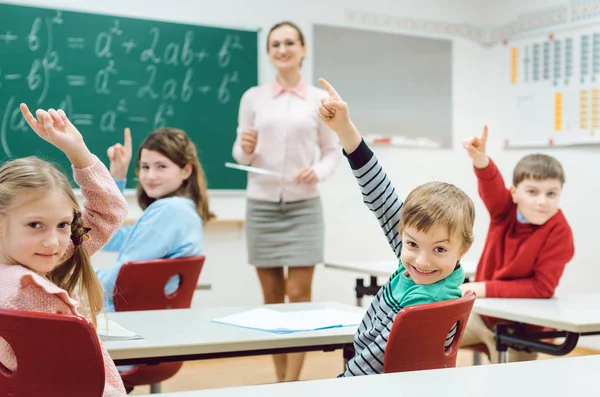 Estudiantes en clase levantando las manos para responder una pregunta — Foto de Stock