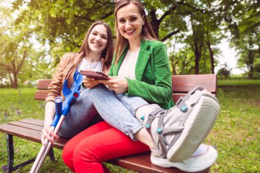 İki en iyi arkadaş, biri yaralı bacaklı, kitap okuyor.