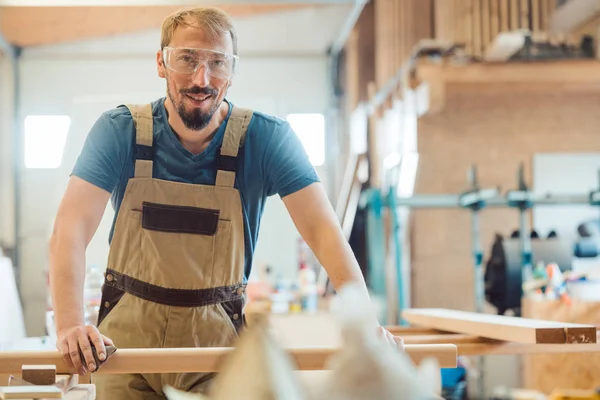 Glücklicher Schreiner in seiner Holzwerkstatt — Stockfoto